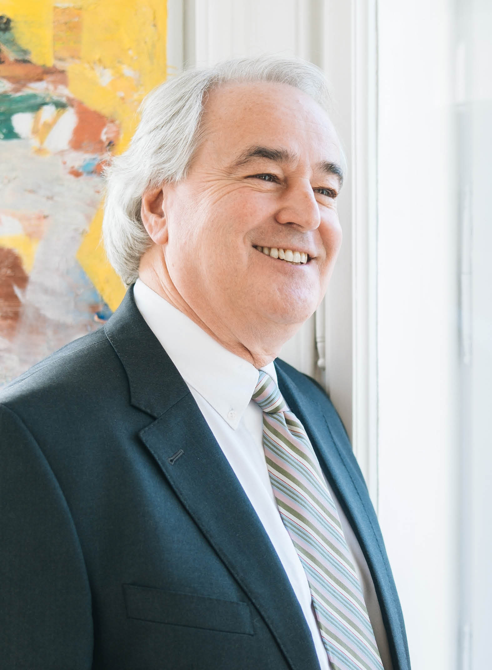 Dr. Roman Kosch steht am Fenster und schaut grinsend nach draußen