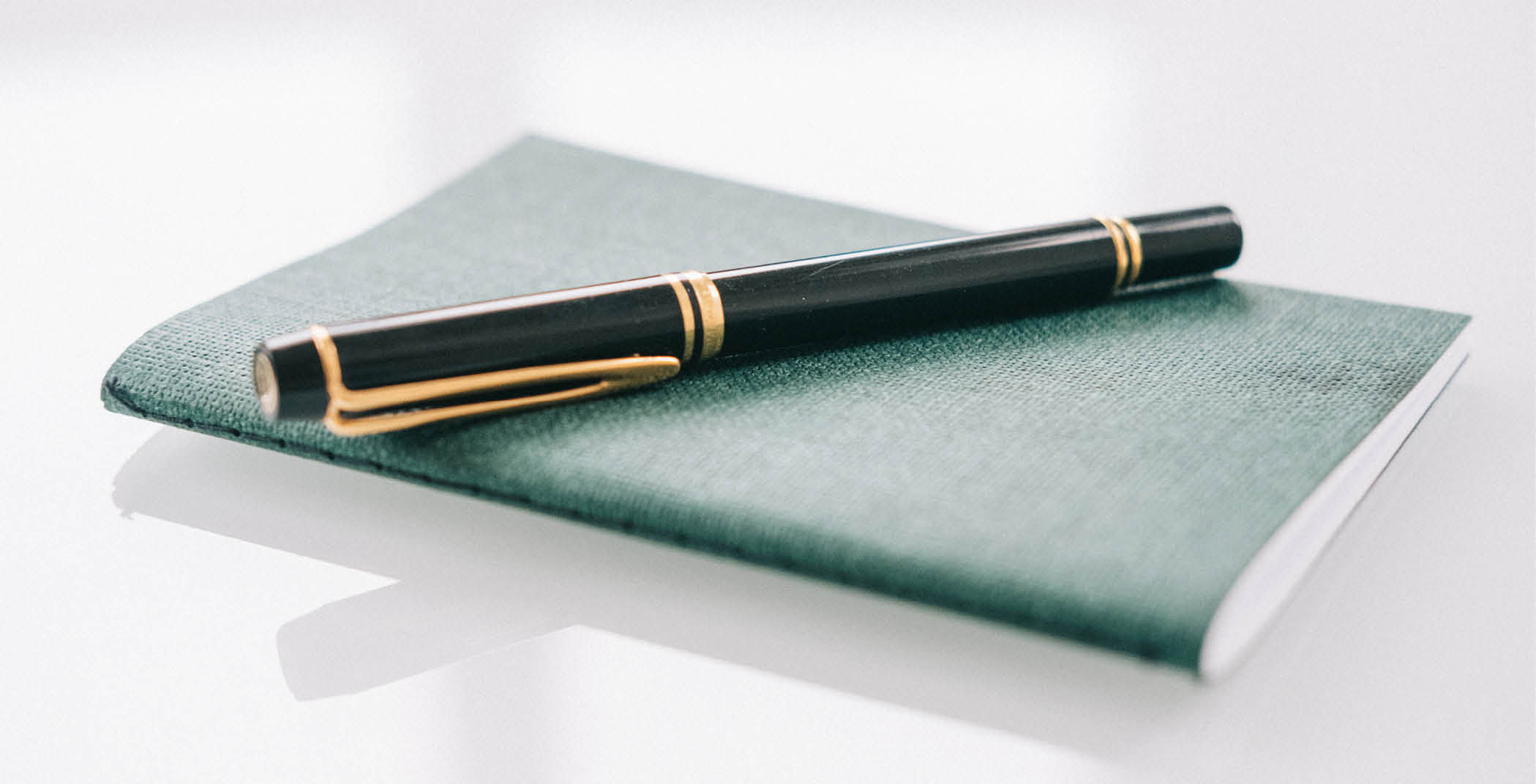 Schwarzer Stift auf grünem Notizblock